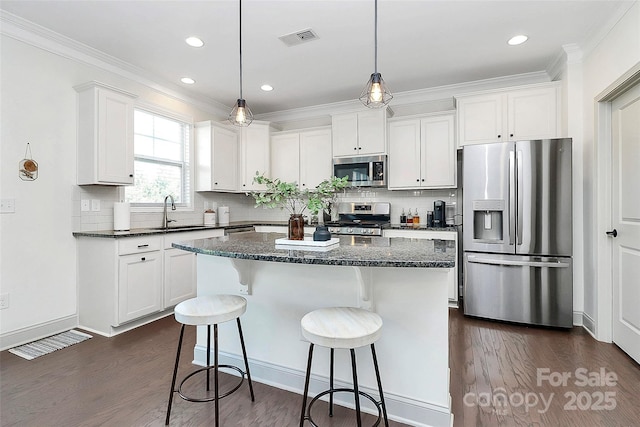 8916 Inverness Bay Rd, Charlotte, NC 28278 - kitchen featuring appliances with stainless steel finishes, a sink, dark wood-type flooring, a kitchen island, and white cabinets
