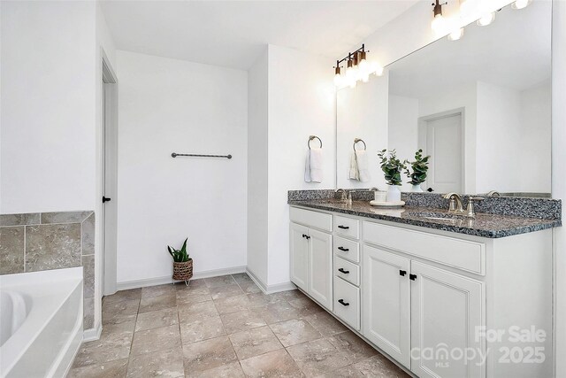 8916 Inverness Bay Rd, Charlotte, NC 28278 - bathroom featuring baseboards, double vanity, a tub to relax in, and stone finish floors