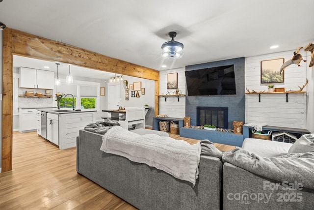 living room with light wood-style flooring, a fireplace, recessed lighting, and beam ceiling