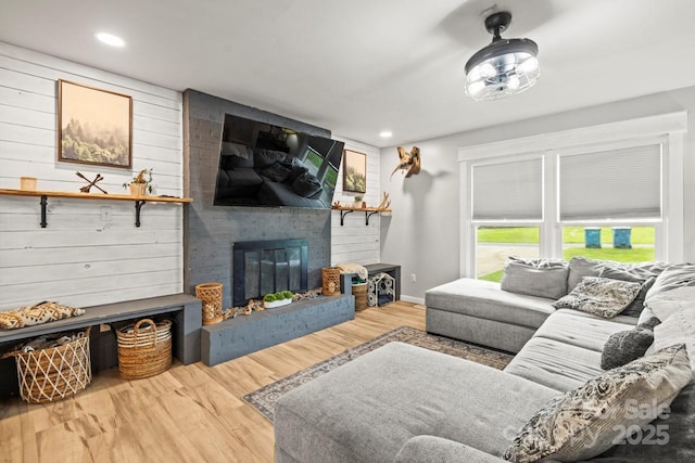 living area with a fireplace, wood finished floors, recessed lighting, and wood walls