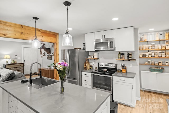 kitchen featuring appliances with stainless steel finishes, a sink, white cabinets, light wood-style floors, and recessed lighting