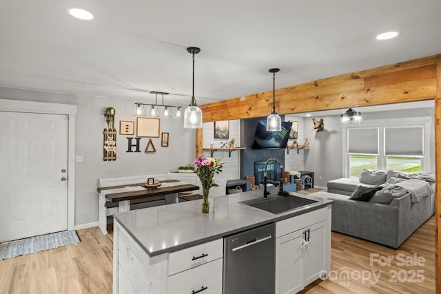 kitchen featuring stainless steel dishwasher, a sink, open floor plan, white cabinetry, and recessed lighting