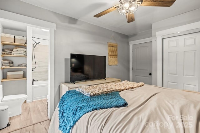 bedroom featuring wood finished floors, a closet, ceiling fan, and ensuite bath