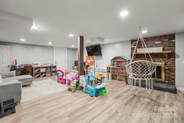 living room featuring wood finished floors, recessed lighting, and a brick fireplace