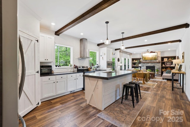 281 Crooked Creek Est, Old Fort, NC 28762 - kitchen with wall chimney exhaust hood, a stone fireplace, stainless steel appliances, dark countertops, and open floor plan