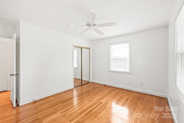 unfurnished bedroom with light wood-style floors, baseboards, a closet, and ceiling fan