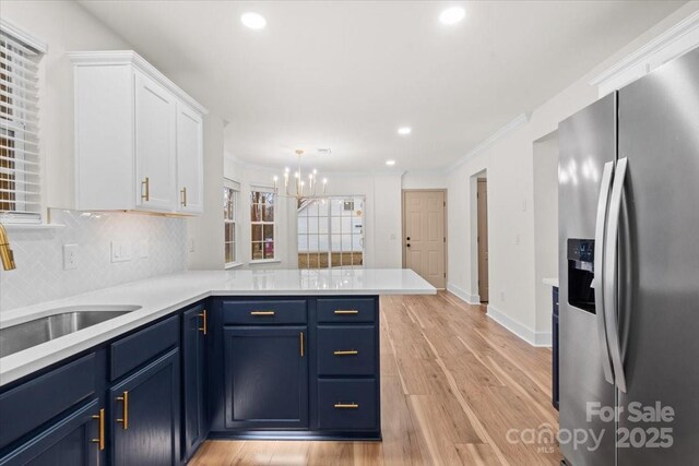 130 Valley Glen Dr, Troutman, NC 28166 - kitchen featuring stainless steel refrigerator with ice dispenser, blue cabinets, white cabinets, a peninsula, and light countertops