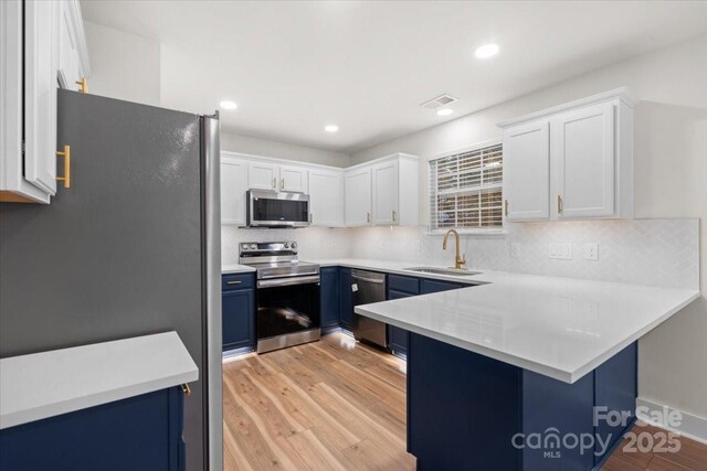 130 Valley Glen Dr, Troutman, NC 28166 - kitchen featuring stainless steel appliances, a sink, blue cabinetry, a peninsula, and tasteful backsplash