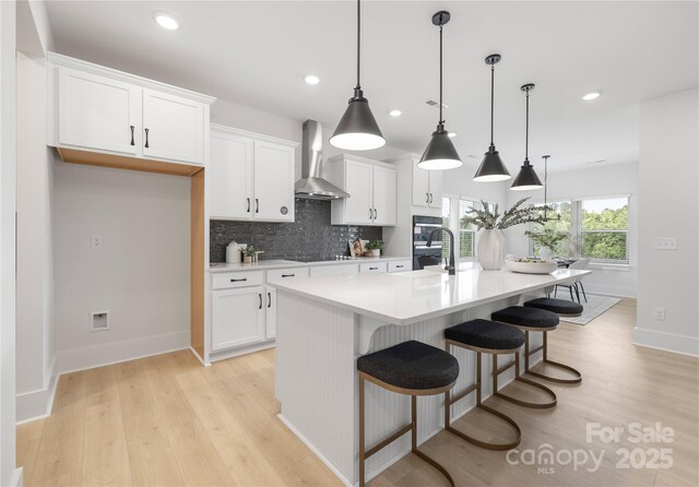 219 Tillery Ln Unit 755, Mount Gilead, NC 27306 - kitchen with wall chimney range hood, baseboards, light wood-type flooring, light countertops, and recessed lighting