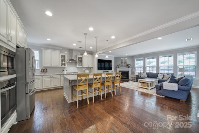 11216 Preservation Ln, Charlotte, NC 28278 - kitchen featuring appliances with stainless steel finishes, wall chimney range hood, a fireplace, crown molding, and open floor plan