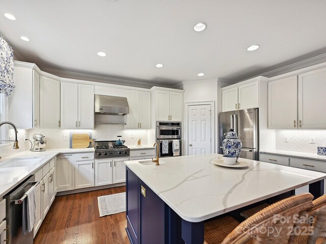 18419 Dembridge Dr, Davidson, NC 28036 - kitchen featuring stainless steel appliances, a sink, wall chimney exhaust hood, a center island, and white cabinets