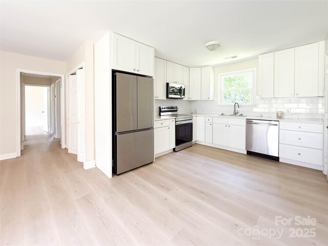 2469 Elkwood Cir, Charlotte, NC 28205 - kitchen with stainless steel appliances, light wood-style flooring, white cabinets, and light countertops