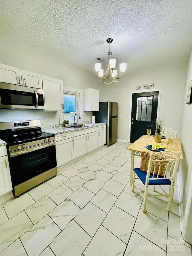 357 Huger St, Cheraw, SC 29520 - kitchen featuring stainless steel appliances, a chandelier, light marble finish flooring, white cabinets, and a textured ceiling