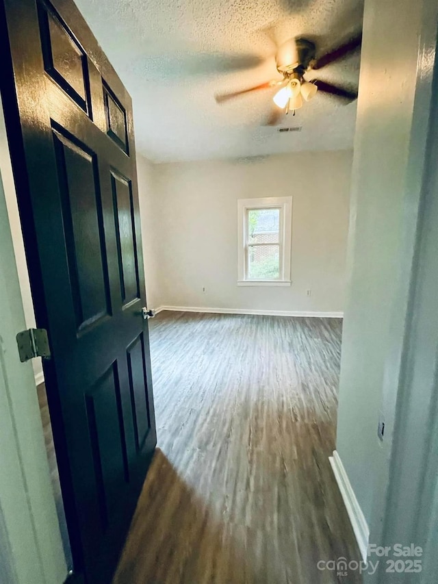 357 Huger St, Cheraw, SC 29520 - empty room with baseboards, dark wood-type flooring, a textured ceiling, and ceiling fan