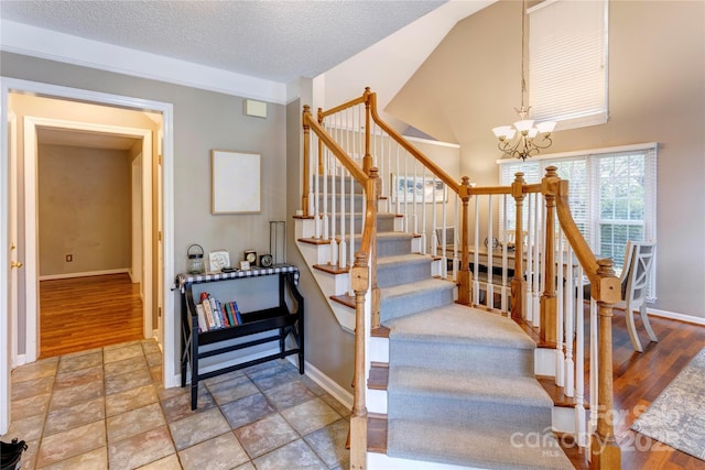 staircase with baseboards, a chandelier, wood finished floors, and a textured ceiling