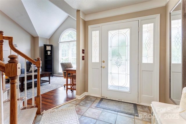 foyer featuring stairway, lofted ceiling, and baseboards