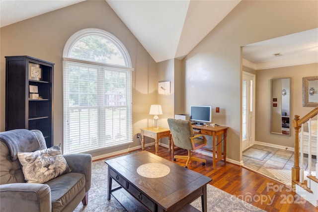 living area featuring lofted ceiling, wood finished floors, baseboards, and a desk