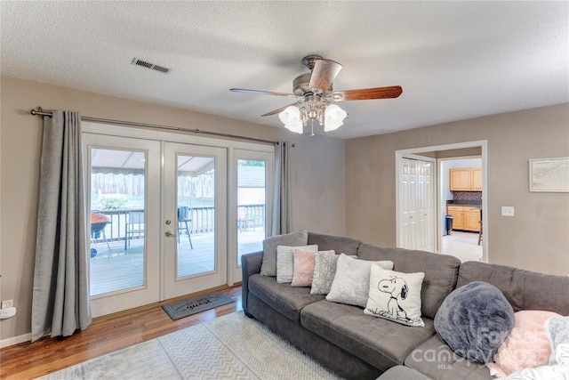 living room with french doors, wood finished floors, ceiling fan, and a textured ceiling