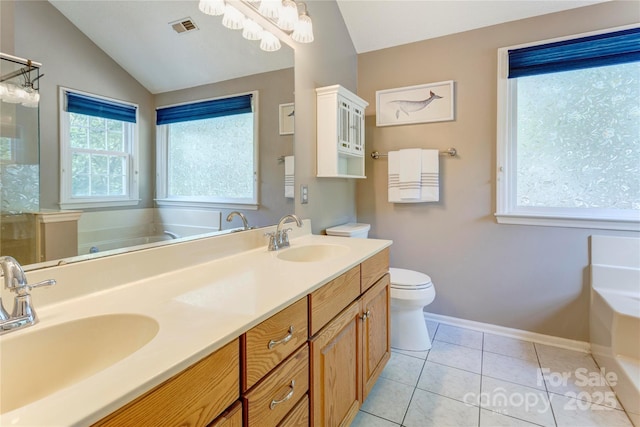 bathroom with a bath, toilet, lofted ceiling, double vanity, and baseboards