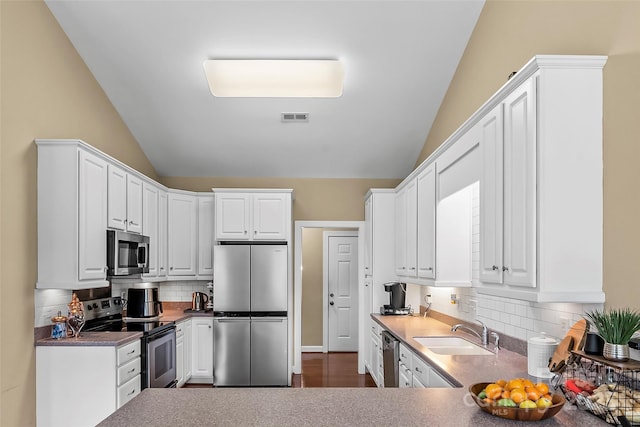 1825 Smyre Farm Rd, Newton, NC 28658 - kitchen featuring appliances with stainless steel finishes, a sink, vaulted ceiling, white cabinetry, and decorative backsplash
