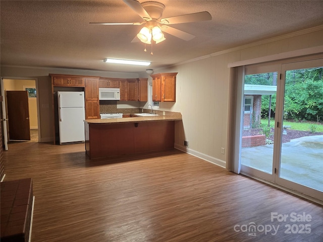 520 Crestview Dr, Albemarle, NC 28001 - kitchen with white appliances, a sink, a peninsula, brown cabinets, and ornamental molding