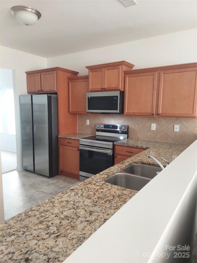 2061 Argentum Ave, Fort Mill, SC 29707 - kitchen with stainless steel appliances, a sink, backsplash, brown cabinetry, and light stone counters