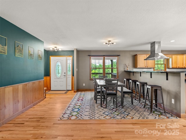 575 Upper Glady Fork Rd, Candler, NC 28715 - dining area featuring light wood finished floors, a textured ceiling, a wainscoted wall, and wooden walls