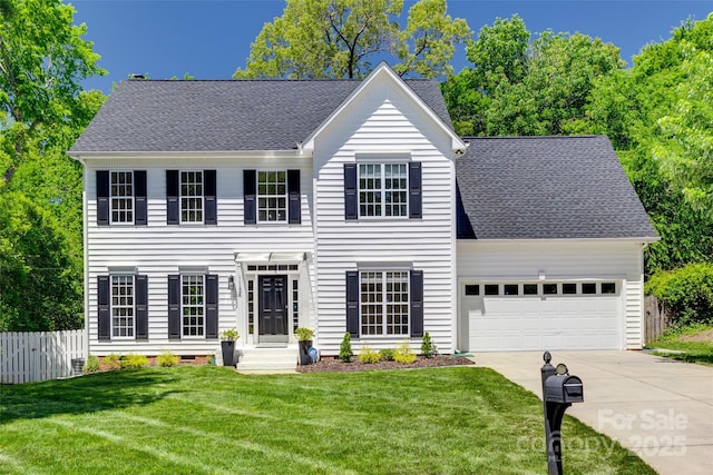 colonial house with an attached garage, concrete driveway, and a shingled roof