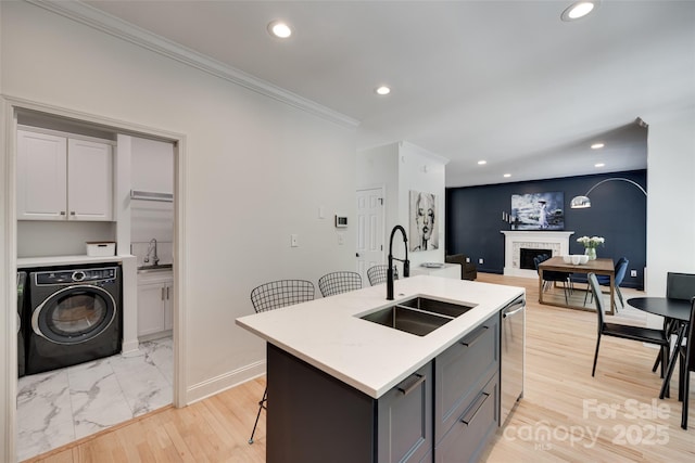kitchen with a sink, washer / clothes dryer, recessed lighting, a fireplace, and light countertops