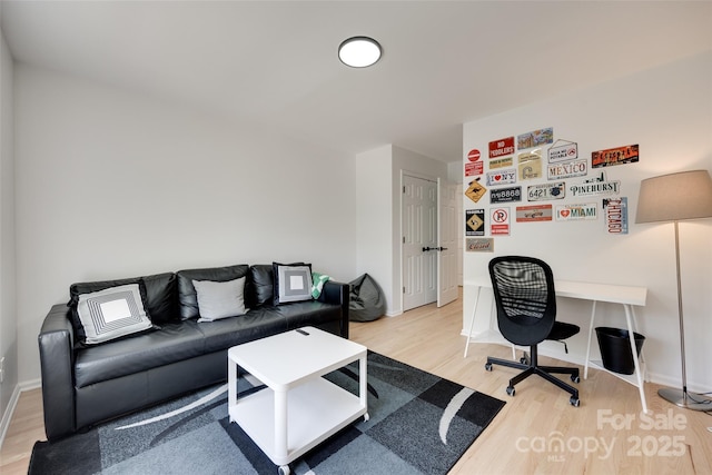 living room featuring light wood-style flooring, an office area, and baseboards