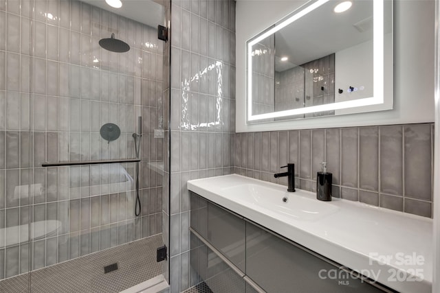full bath featuring a stall shower, tile walls, and vanity