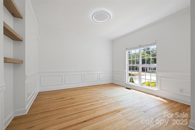 1134 Blueberry Ln, Charlotte, NC 28226 - spare room featuring light wood-style flooring, ornamental molding, a wainscoted wall, and a decorative wall