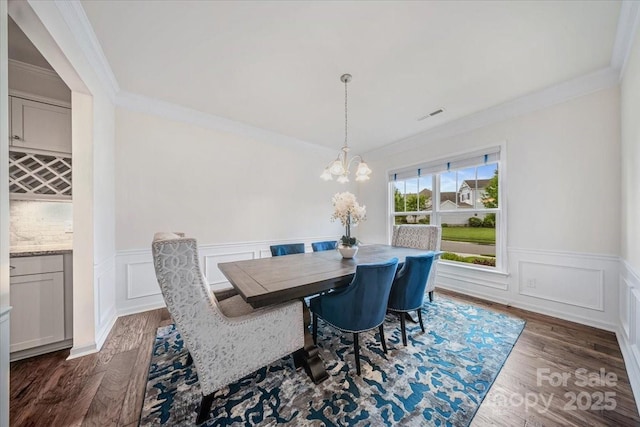 5366 Meadowcroft Way, Fort Mill, SC 29708 - dining area featuring crown molding, dark wood-style flooring, a chandelier, a decorative wall, and wainscoting