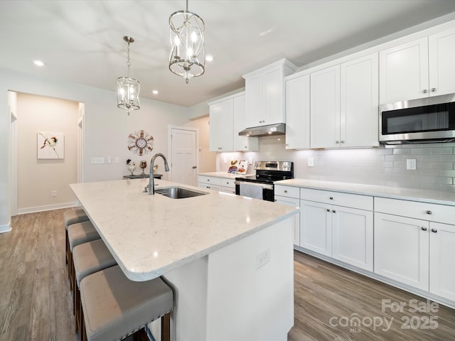 1456 Augustus Beamon Dr, Indian Trail, NC 28079 - kitchen with appliances with stainless steel finishes, a sink, under cabinet range hood, an island with sink, and decorative backsplash
