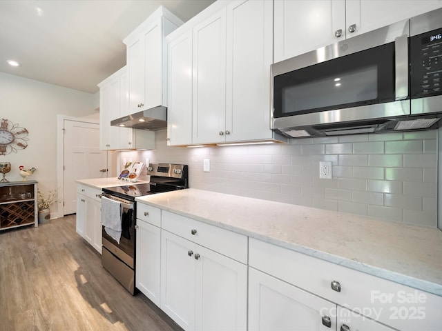 1456 Augustus Beamon Dr, Indian Trail, NC 28079 - kitchen with stainless steel appliances, under cabinet range hood, light wood-style flooring, white cabinets, and decorative backsplash
