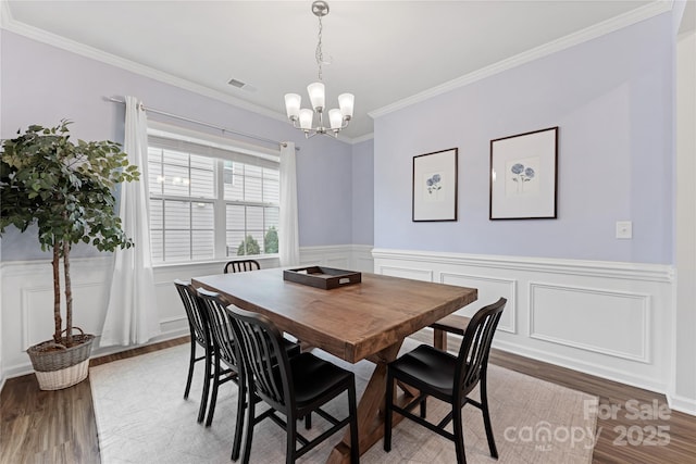 15630 Oleander Dr, Charlotte, NC 28278 - dining room featuring light wood-style flooring, a chandelier, ornamental molding, wainscoting, and a decorative wall