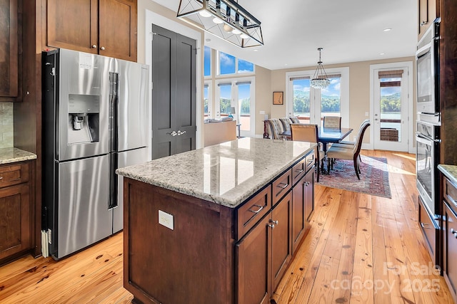204 Ridge Dr Unit 12 12-1 12-2, Troy, NC 27371 - kitchen featuring appliances with stainless steel finishes, light wood finished floors, a kitchen island, decorative light fixtures, and light stone counters