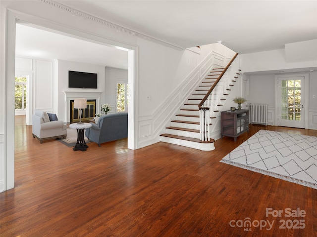 316 Vanderbilt Rd, Asheville, NC 28803 - entrance foyer featuring radiator, wood finished floors, stairs, a decorative wall, and a glass covered fireplace