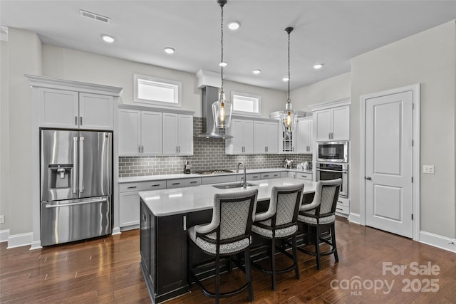 9750 Briarwick Ln, Charlotte, NC 28277 - kitchen with appliances with stainless steel finishes, light countertops, wall chimney exhaust hood, a center island with sink, and decorative backsplash