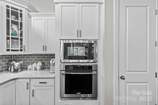 9750 Briarwick Ln, Charlotte, NC 28277 - kitchen featuring appliances with stainless steel finishes, white cabinetry, light countertops, and glass insert cabinets