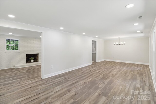 unfurnished living room with a fireplace, a chandelier, crown molding, wood finished floors, and recessed lighting