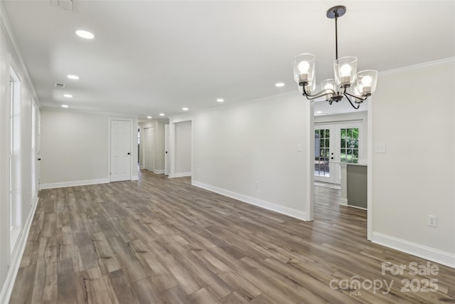 empty room with recessed lighting, baseboards, wood finished floors, a chandelier, and crown molding