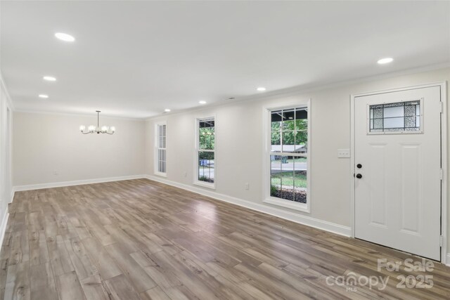 entryway featuring a chandelier, crown molding, wood finished floors, baseboards, and recessed lighting
