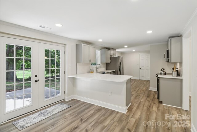 kitchen with stainless steel fridge with ice dispenser, gray cabinetry, a sink, light countertops, and crown molding