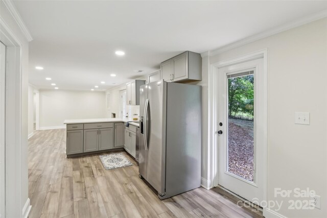kitchen with stainless steel refrigerator with ice dispenser, gray cabinetry, a peninsula, light wood finished floors, and recessed lighting