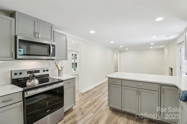 kitchen featuring stainless steel appliances, gray cabinets, light wood-type flooring, recessed lighting, and light countertops
