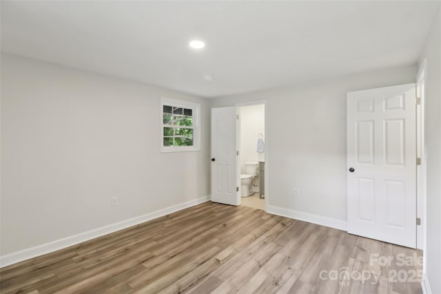 unfurnished bedroom featuring light wood finished floors, baseboards, recessed lighting, and connected bathroom