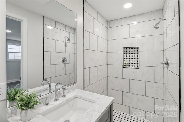 bathroom featuring tiled shower, vanity, and recessed lighting