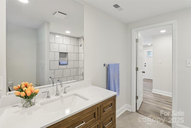 bathroom featuring baseboards, vanity, recessed lighting, and wood finished floors