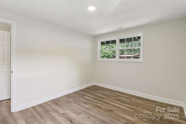 empty room with baseboards, wood finished floors, and recessed lighting